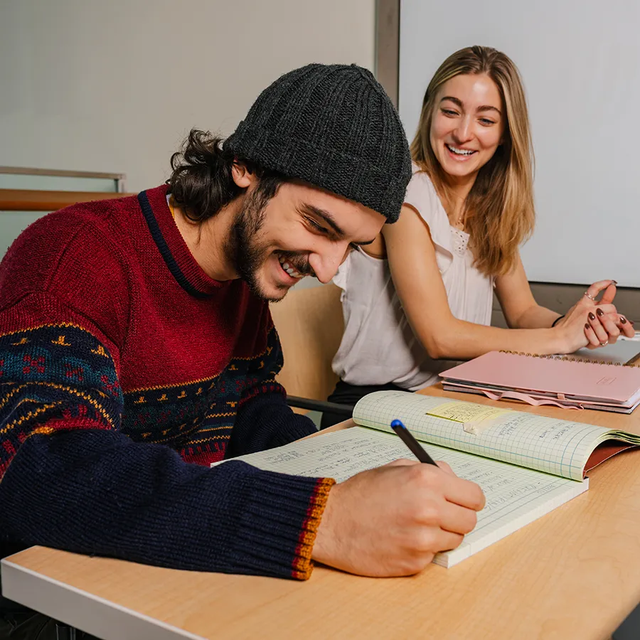 Two students laugh while working together.
