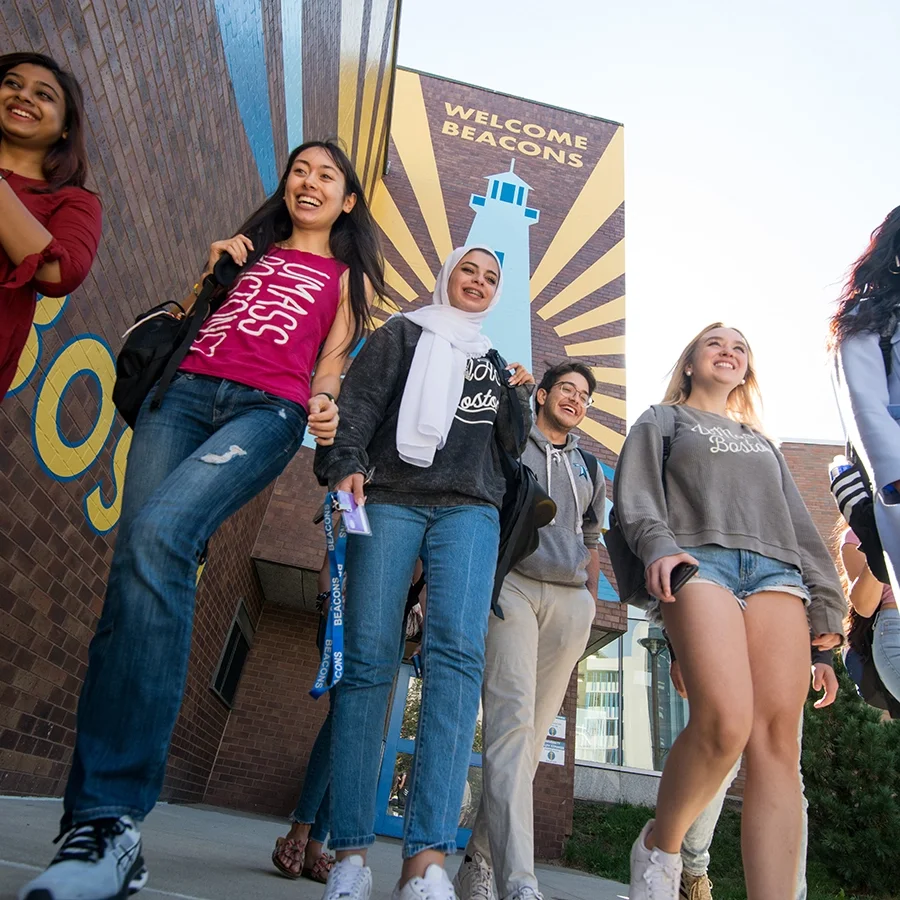 Four students walking in front of a mural that reads 